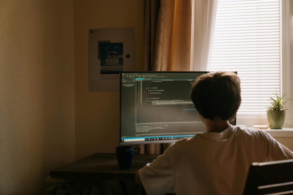 Deweloper pracujący przed monitorem z kodem źródłowym w przytulnym domowym biurze – praca zdalna dla programistów na cvsearch.pl