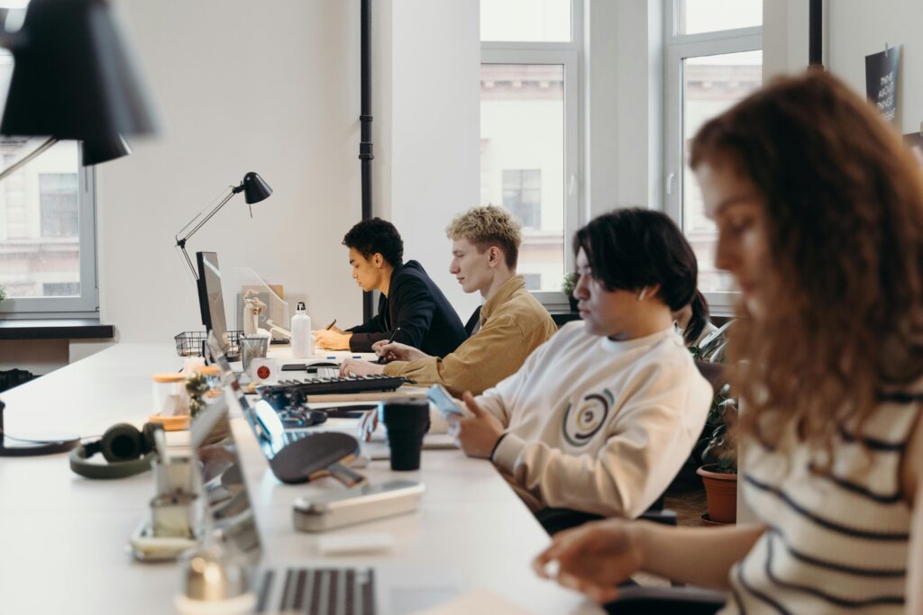 Grupa młodych specjalistów pracujących przy laptopach w jasnym, nowoczesnym biurze typu coworking – oferty pracy i rekrutacja na cvsearch.pl