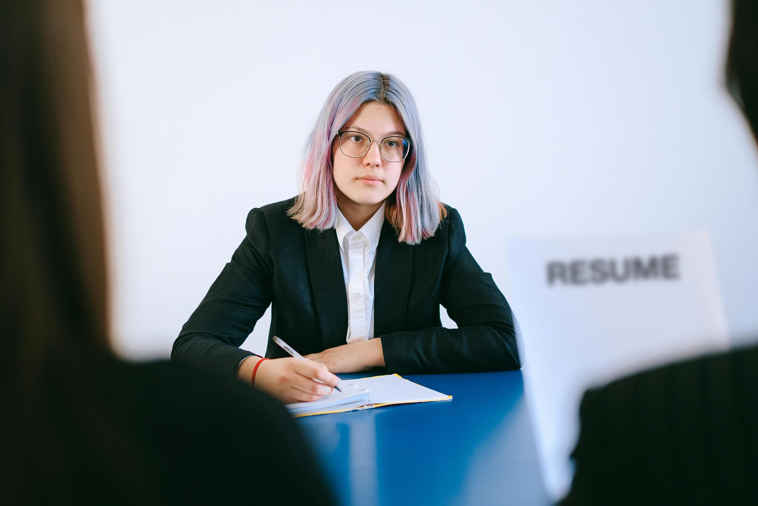 Młoda kobieta z fioletowymi włosami w czarnym żakiecie podczas rozmowy kwalifikacyjnej przed dokumentem "Resume" – profesjonalna rekrutacja i doradztwo kariery na cvsearch.pl