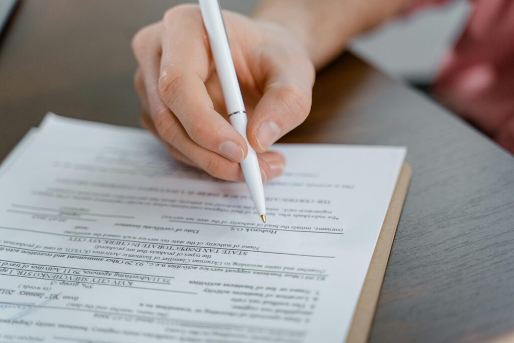 Dłoń trzymająca biały długopis nad kwestionariuszem osobowym – profesjonalne procesy rekrutacyjne i wsparcie HR na cvsearch.pl