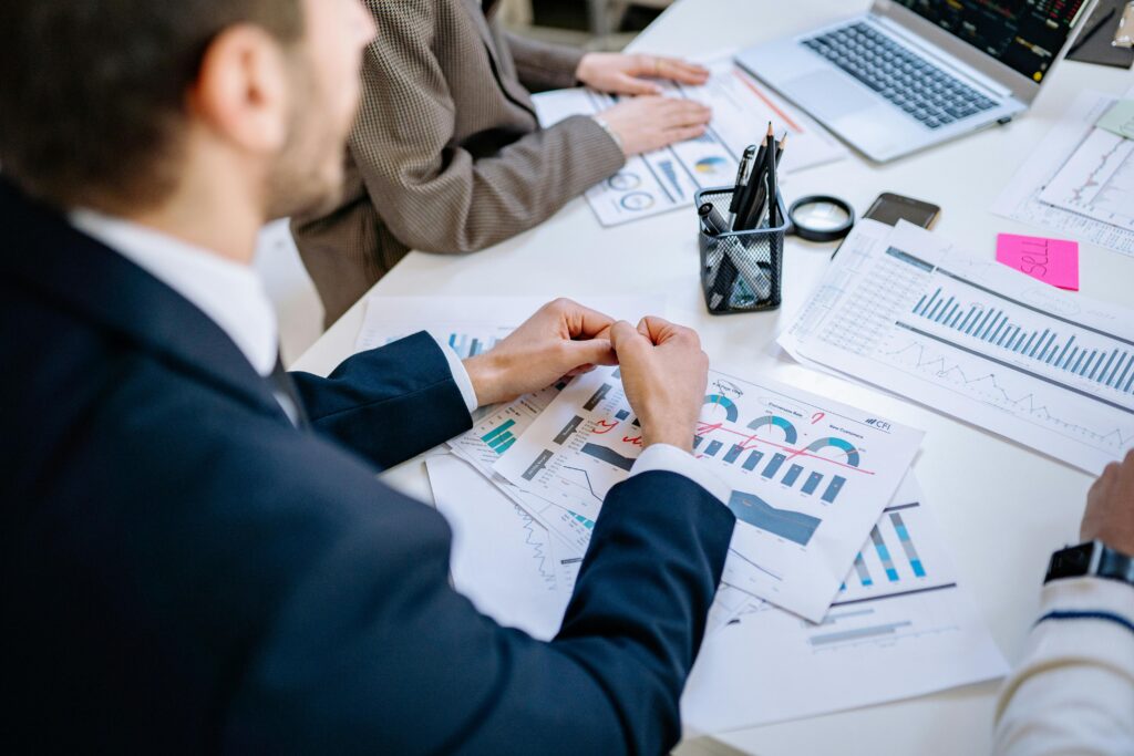 Tekst alternatywny: Specjaliści w garniturach analizujący wykresy i raporty finansowe podczas spotkania biznesowego – rekrutacja analityków i strategów na cvsearch.pl