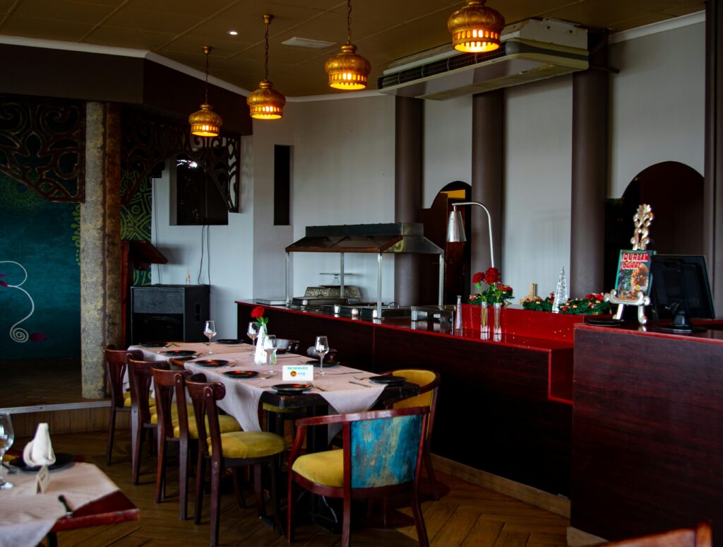 Wnętrze restauracji z przygotowanymi stolikami, ladą i oświetleniem, symbolizujące pracę w gastronomii oraz atmosferę zespołu.